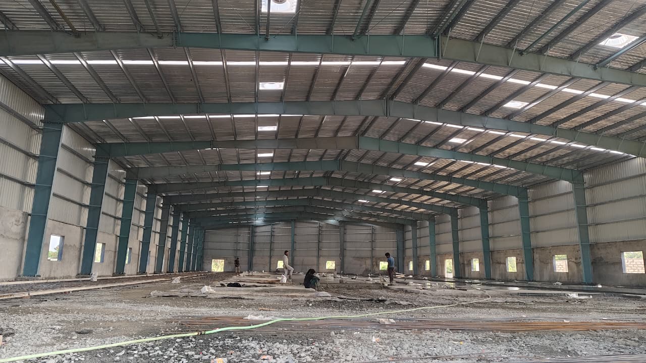 expertly engineered PEB interior - designed for maximum column-free space and structural efficiency. multi-span pre-engineered building interior featuring optimized steel portal frames and polycarbonate skylights for industrial warehouse design.