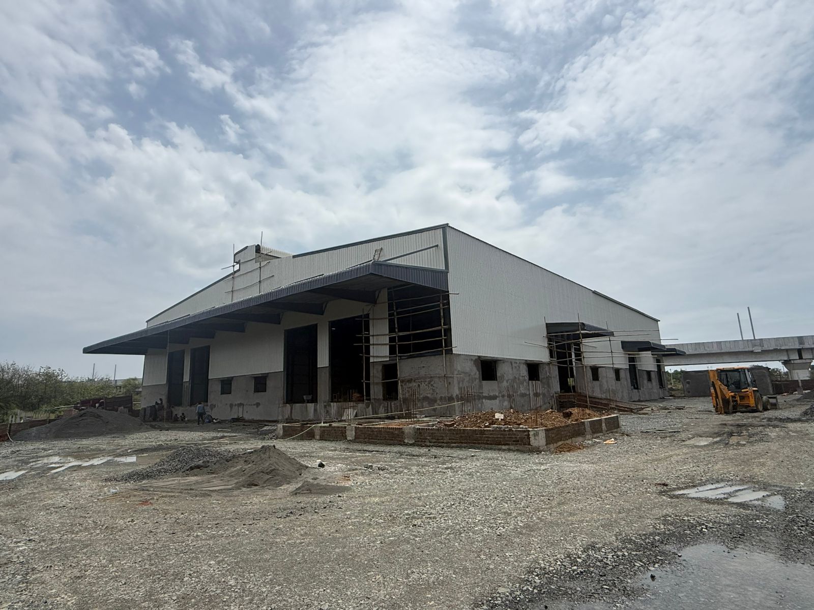 Custom-designed PEB warehouse under construction by SHREESES On-site construction of a custom-designed Pre-Engineered Building warehouse with industrial wall cladding by SHREESES, leading PEB consultants.